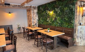 Der Raum zeigt rustikale Holzmöbel und eine grüne Wand aus Pflanzen, die eine einladende Atmosphäre schaffen.
