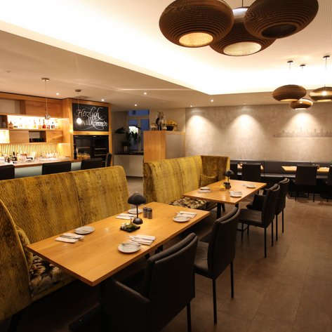 Ein stilvolles Restaurant mit modernen Möbeln, hellem Licht und einem einladenden Barbereich im Hintergrund.
