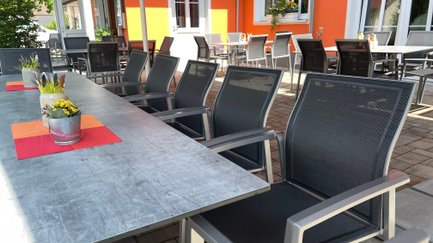 Gemütliche Terrasse eines Lokals, mit eleganten Stühlen und Tischen bereit für Gäste.