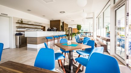 Die Inneneinrichtung des Lokals zeigt elegante Tische und Stühle, ergänzt durch eine offene Bar, die zur Geselligkeit einlädt.