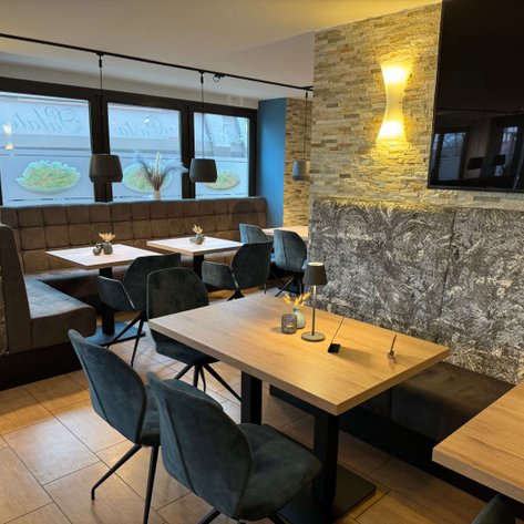 Elegante Restaurant-Einrichtung mit bequemen Stühlen und stilvollem Holzfußboden, ideal für geselliges Beisammensein.