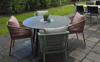 Ein gemütlicher Außenbereich mit einem runden Tisch und farbigen Stühlen, ideal für entspannte Stunden im Freien.