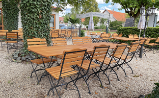 Eine gemütliche Terrasse mit Holzmöbeln und einem schattenspendenden Baum, ideal für entspannte Nachmittage.