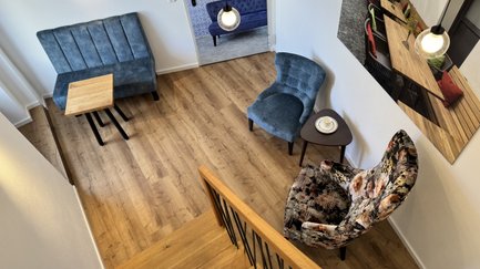 Ausstellungsraum mit blauen und gemusterten Sesseln und einem Holztisch.