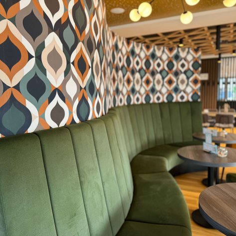 Die stilvolle Restaurant-Atmosphäre ist geprägt von einer geschwungenen grünen Bank und kreativen Wandverkleidungen.