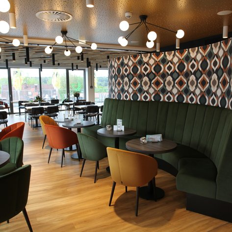 Die stilvolle Restaurant-Atmosphäre ist geprägt von einer geschwungenen grünen Bank und kreativen Wandverkleidungen.