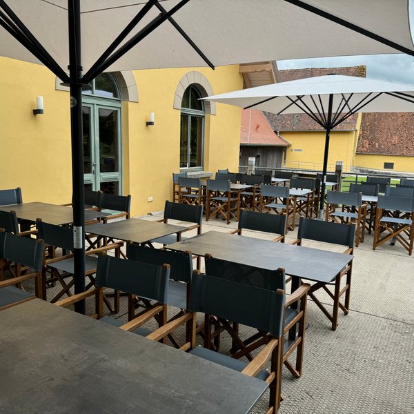 Die Terrasse bietet eine gemütliche Atmosphäre, mit vielen Tischen und Stühlen und großen Sonnenschirmen, ideal für gesellige Zusammenkünfte.