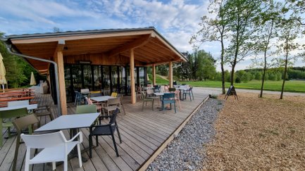 Auf der Terrasse des Cafés warten bunte Stühle und Tische auf Gäste, die die entspannte Atmosphäre im Freien genießen möchten.