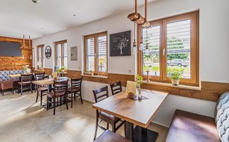 Ein einladendes Café mit einem rustikalen Dekor, wo natürliches Licht durch die Fenster strömt.