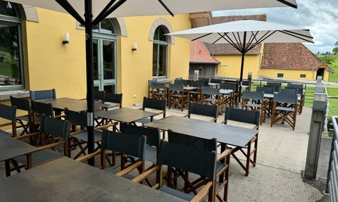 Die Terrasse bietet eine gemütliche Atmosphäre, mit vielen Tischen und Stühlen und großen Sonnenschirmen, ideal für gesellige Zusammenkünfte.
