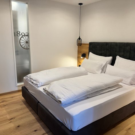 Elegante Schlafzimmereinrichtung mit einer sanften Beleuchtung über einem Bett in neutralen Farbtönen.