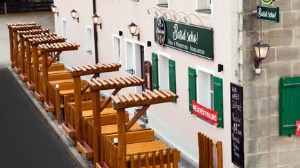 Das gemütliche Biergarten-Ambiente lädt mit Holzmöbeln und einer einladenden Fassade zum Verweilen ein.