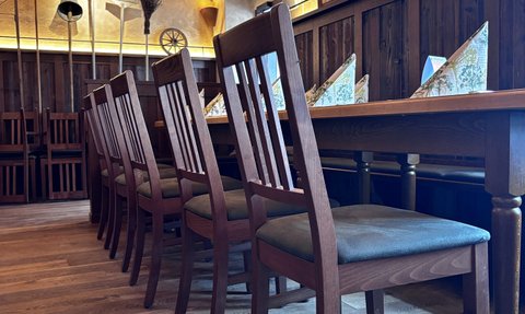Ein rustikales Restaurant mit Holztischen und Stühlen, die auf einem warmen Holzboden angeordnet sind.