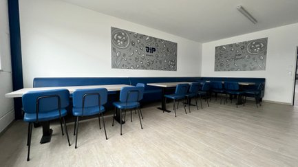 Die Einrichtung umfasst elegante blaue Stühle und Tische aus hellem Holz, ideal für geselliges Beisammensein.