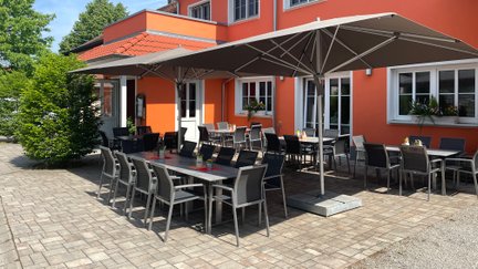 Gemütliche Terrasse eines Lokals, mit eleganten Stühlen und Tischen bereit für Gäste.