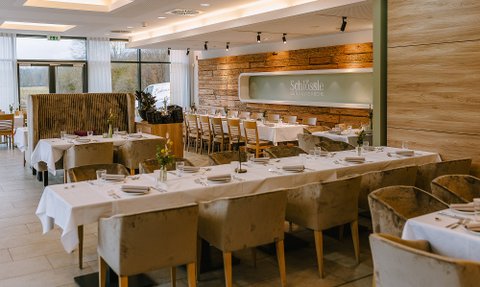 Der Essbereich eines Restaurants, das mit eleganten Möbeln und einer warmen Farbpalette eine entspannte Stimmung vermittelt.