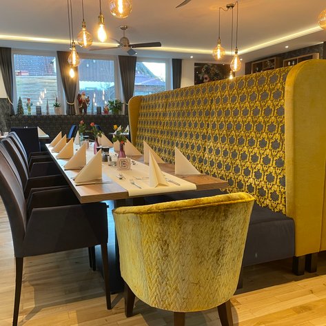 Die gemütliche Atmosphäre des Restaurants zeigt eine ansprechend dekorierte lange Tafel und stilvolle Sitzgelegenheiten.