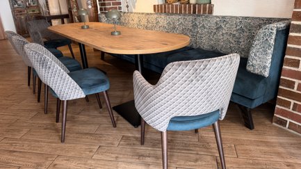 Der Innenraum zeigt eine gemütliche Sitzecke mit einer blauen Bank, einem großen Tisch und modernen Vollpolsterstühlen.