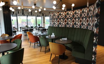 Die stilvolle Restaurant-Atmosphäre ist geprägt von einer geschwungenen grünen Bank und kreativen Wandverkleidungen.