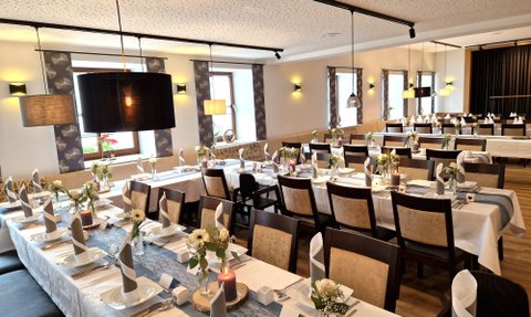 Ein stilvoll gestalteter Raum mit langen Holztischen und eleganten Stühlen, ideal für gesellige Zusammenkünfte oder Veranstaltungen.