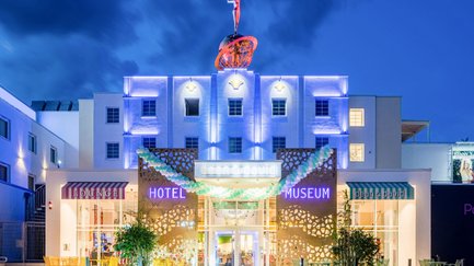 Das moderne Foyer eines Hotels bei Nacht, beleuchtet mit bunten Lichtern und umgeben von schicken Außenbereichen.