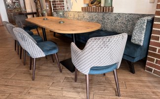 Der Innenraum zeigt eine gemütliche Sitzecke mit einer blauen Bank, einem großen Tisch und modernen Vollpolsterstühlen.