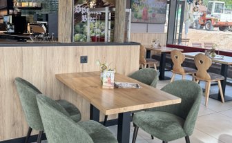 Der Innenraum eines Cafés zeigt einen eleganten Tisch mit einer kleinen Blumendekoration und einem auffälligen Lampendesign über dem Tisch.