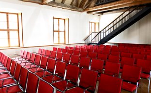 Saalbestuhlung mit rot gepolsterten Stühlen