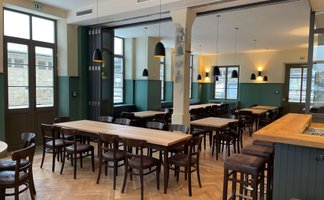 Helles, klassisches Restaurant mit Holzstühlen und großen Fenstern, das eine einladende Atmosphäre schafft.