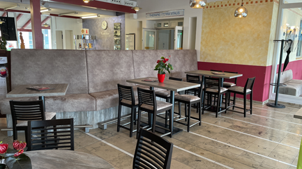 Bequeme Sitzbänke in einem hellen Café, umgeben von stilvollen Tischen und einer eleganten Dekoration an der Wand.
