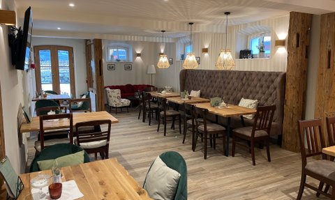 Verschiedene Platzmöglichkeiten im Restaurant, darunter ein gemütlicher Bereich mit einem roten Sofa und charmanten Dekorationen.