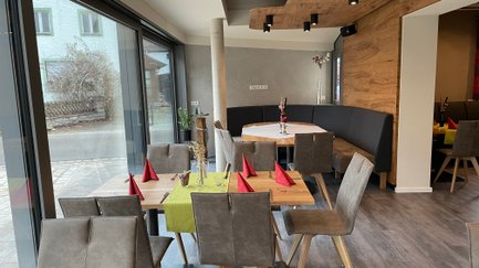 Flexible Sitzmöglichkeiten durch eine gepolsterte Bank und Stühle, ideal für geselliges Beisammensein in einem modern gestalteten Raum.