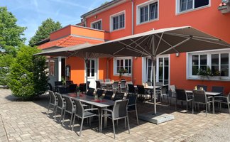 Gemütliche Terrasse eines Lokals, mit eleganten Stühlen und Tischen bereit für Gäste.