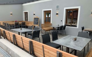 Gemütlicher Außenbereich mit Holz- und Metallmöbeln, der eine angenehme Atmosphäre für Gäste schafft.