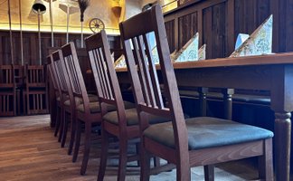 Ein rustikales Restaurant mit Holztischen und Stühlen, die auf einem warmen Holzboden angeordnet sind.