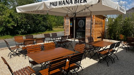 Ein gemütlicher Biergarten mit rustikalen Holzmöbeln und Sonnenschirmen bietet Platz für zahlreiche Gäste.
