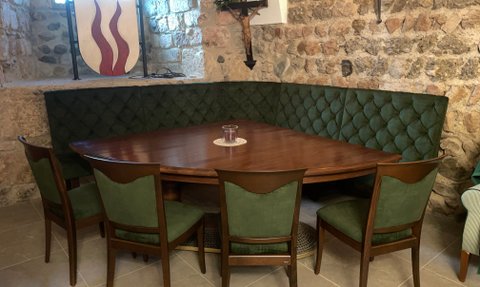 In einem einladenden Raum finden sich ein ovaler Tisch und gepolsterte grüne Sitzgelegenheiten in einer gemütlichen Ecke.
