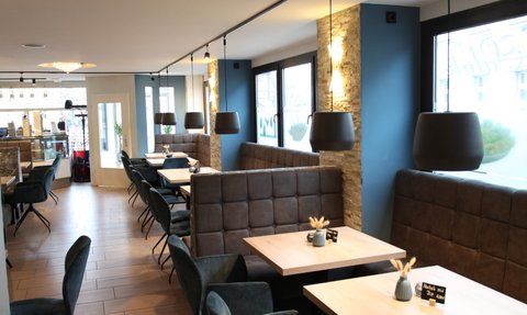 Elegante Restaurant-Einrichtung mit bequemen Stühlen und stilvollem Holzfußboden, ideal für geselliges Beisammensein.