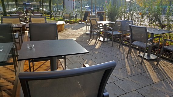 Outdoor-Bereich mit Tischen und Stühlen, in grau gehalten.