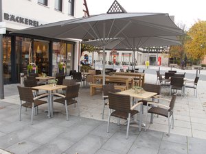 Quadratischer Terrassenschirm mit dunklem Segel.