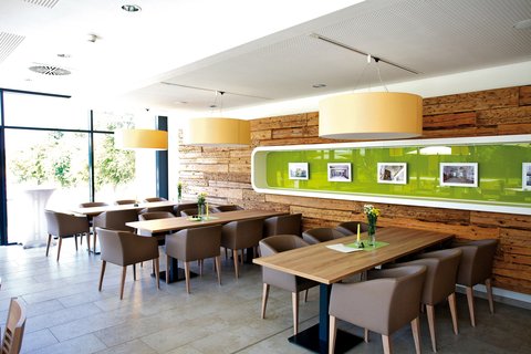 Gastraum mit gepolsterten Stühlen, Holztischen und einer futuristisch grün-braunen Wand im Schlössle in Nördlingen