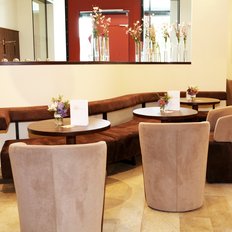 Cafe-Bereich mit runden Stühlen und eine kurvigen Sitzbank in Grau-Rot-Tönen