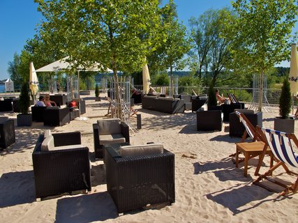 Mehrere Rattan-Stühle im Sand bei gutem Wetter